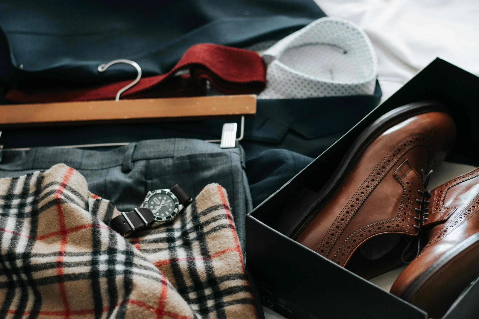 fashion composition with clothing, accessories and brown shoes in box, checkered socks, black watch, t-shirts hanging on wooden rack